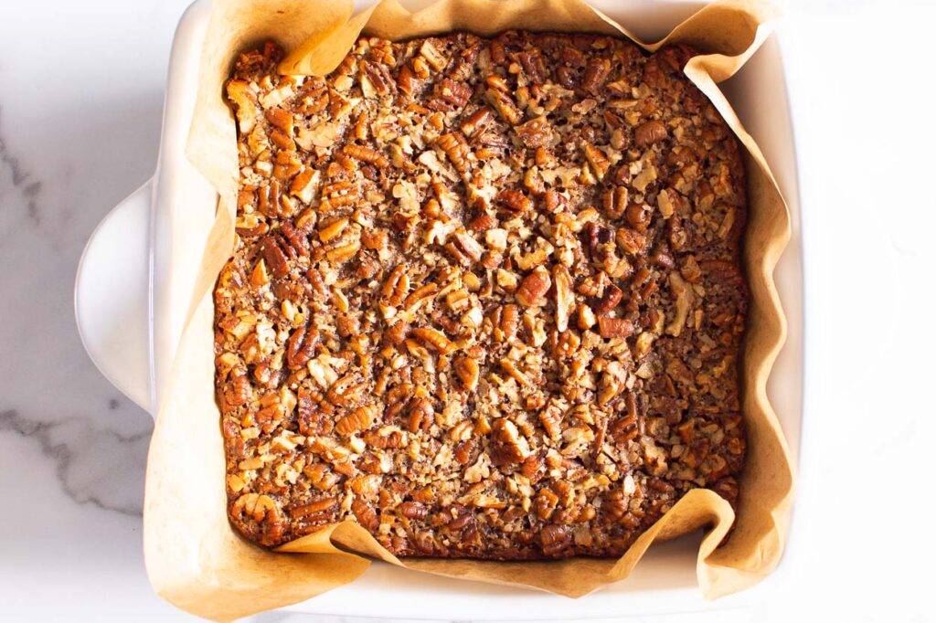 Baked healthy pecan pie bars in parchment lined pan. 