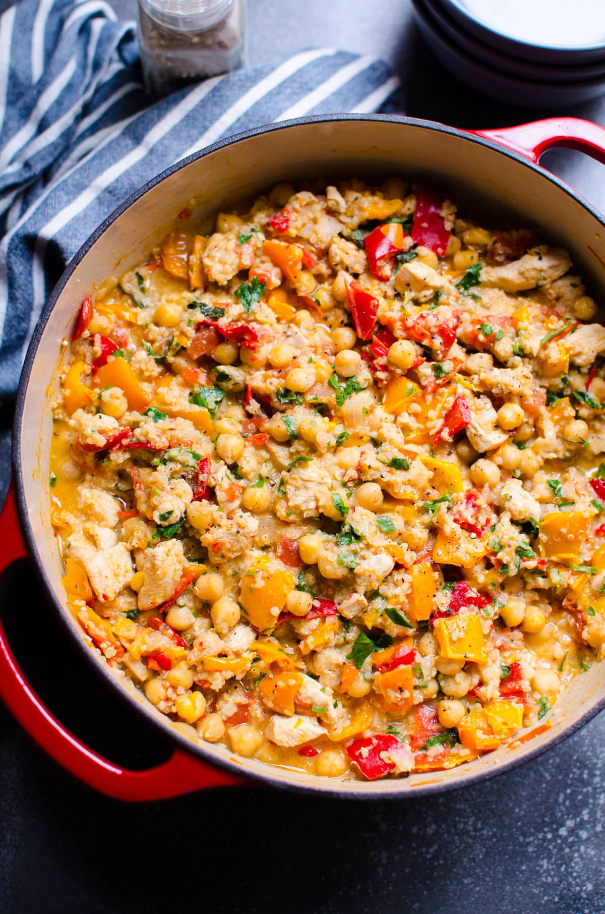 Chicken chickpea stew in a pot. Towel and pepper mill on a counter.