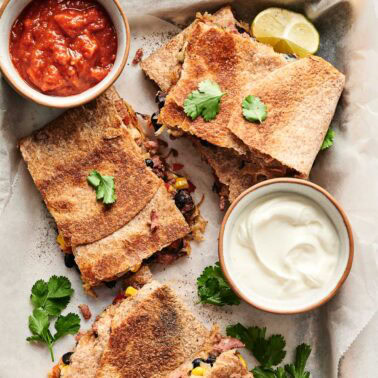 Sheet pan quesadillas served with sour cream and salsa.