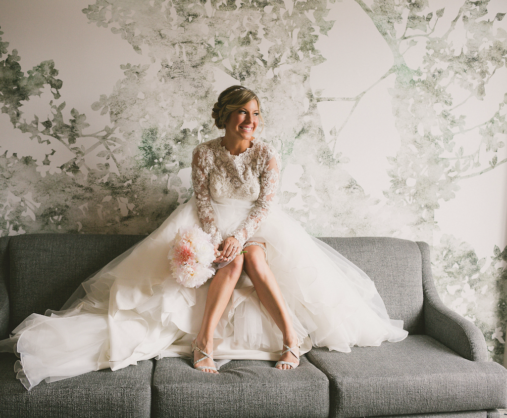 Bride with a flower bouquet sitting on a sofa at The Grove Hotel