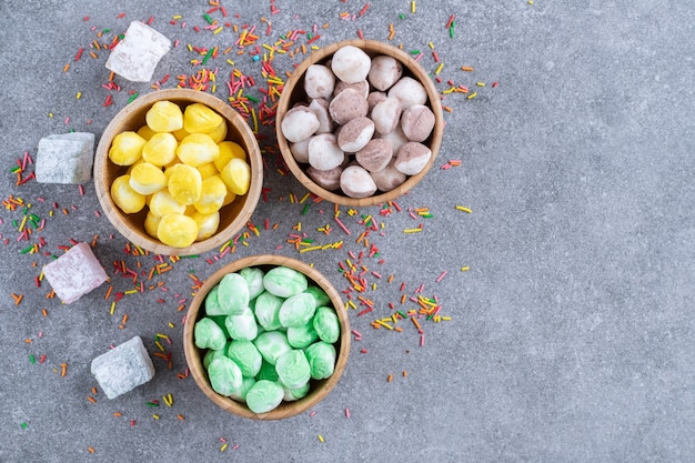 Free Photo | Three bowls of colorful candies on marble surface