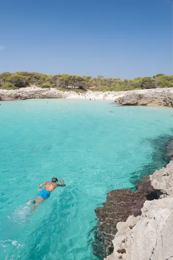 Man zwemt in het heldere zeewater van Menorca