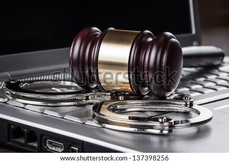 handcuffs and judge gavel on computer cyber crime concept