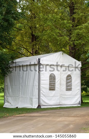 A white party or event tent on a meadow in a public park