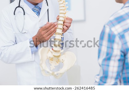 Doctor showing anatomical spine to his patient in medical office