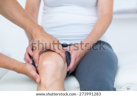 Doctor examining his patients knee in medical office