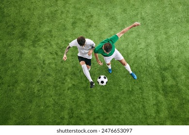 Aerial view. Two male soccer players compete for possession of ball on green lush playground. Concept of professional sport, championship, tournament, final match, movement. Ad