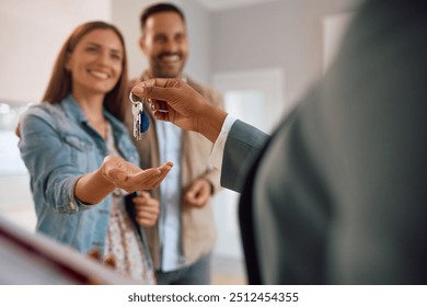 Close up of happy couple receiving keys of their new home from real estate agent. 