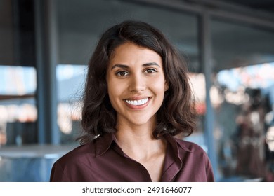 Closeup headshot face portrait of beautiful successful hispanic young business woman looking confident at camera. Smiling latin or eastern middle age female ceo leader businesswoman standing in office