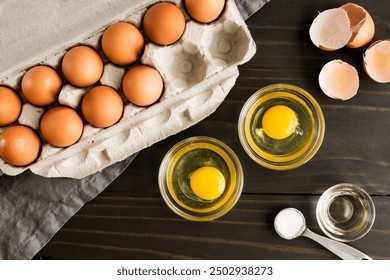 Cracked Eggs in Small Glass Bowls: Dishes with cracked eggs next to a paper egg carton and broken brown egg shells