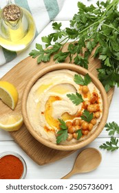 Delicious hummus with olive oil, chickpeas and parsley served on white wooden table, flat lay