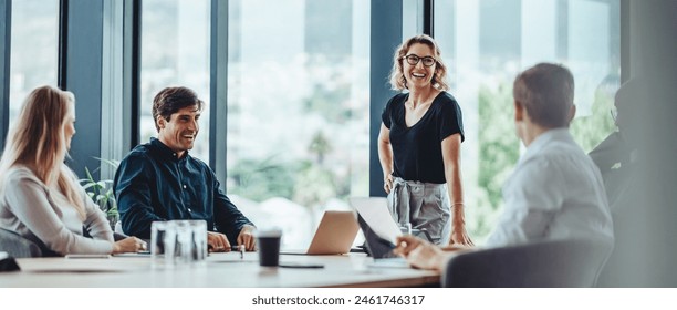 Group of colleagues engaging in a discussion during a business meeting in a conference room. Happy business people, men and women, collaborating and working towards their shared goals.