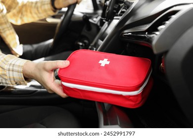 Man with first aid kit inside car, closeup