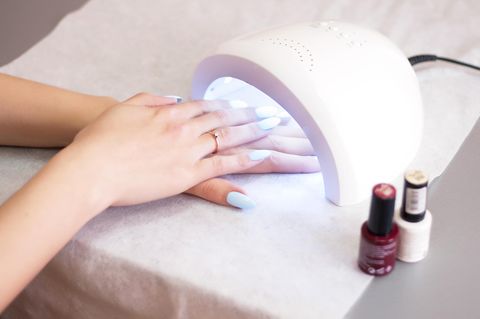 Frau härtet UV-Nagellack unter einem Nagelhärter