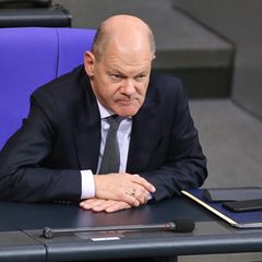 Kanzler Olaf Scholz sitzt am Tag der Vertrauensfrage im Bundestag, hält Zeigefinger an die Schläfe.