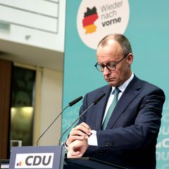 Friedrich Merz schaut bei einer Pressekonferenz auf seine Uhr.