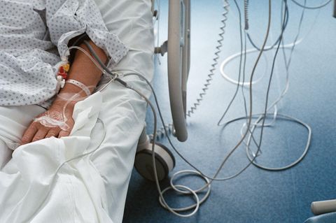 Ein Patient mit einer Infusion im Arm liegt in einem Krankenhausbett