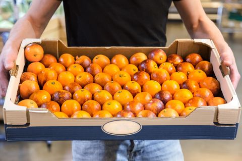 Ein Mann trägt eine Stiege Orangen