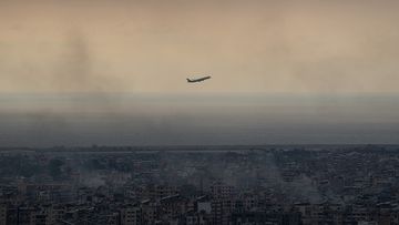 A plane departing Beirut international airport flies near smoke from Israeli airstrikes in Beirut.