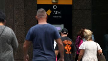 People move past a Commonwealth Bank ATM machine.