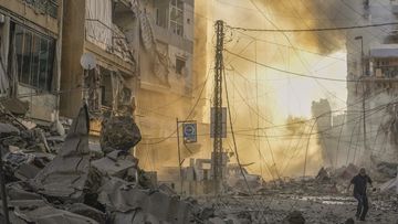 A man runs for cover as a smoke raises in the background following an Israeli airstrike in Dahiyeh, Beirut, Lebanon, Friday, Oct. 4, 2024 