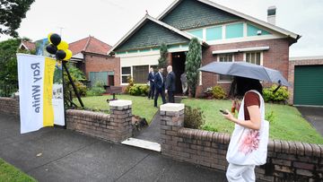 Someone with an umbrella walks past an auction.