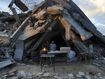 A man sells bread under the destruction of his bakery destroyed by the Israeli air and ground offensive in Jabaliya, Gaza Strip.