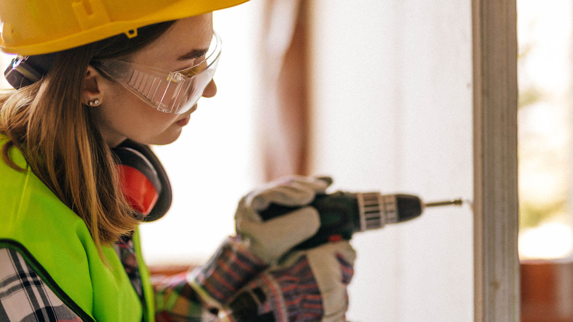 A woman drilling a wood panel