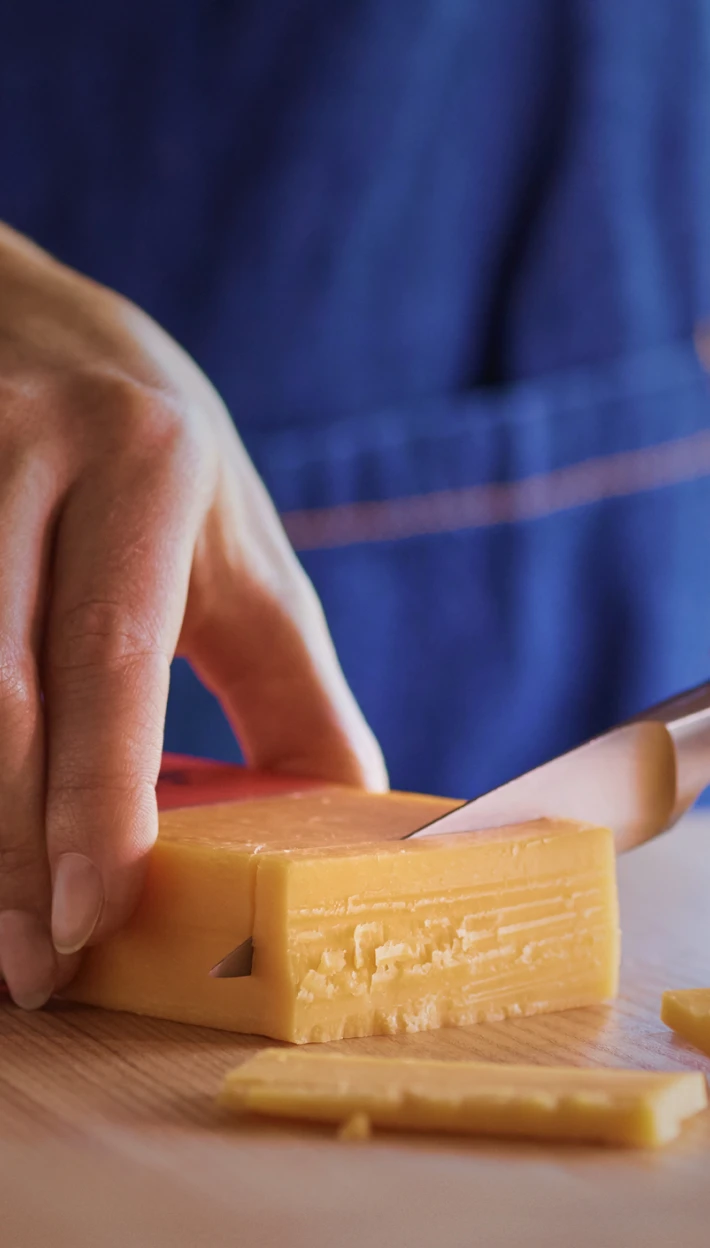 Hands cutting Tillamook Cheddar Cheese Block