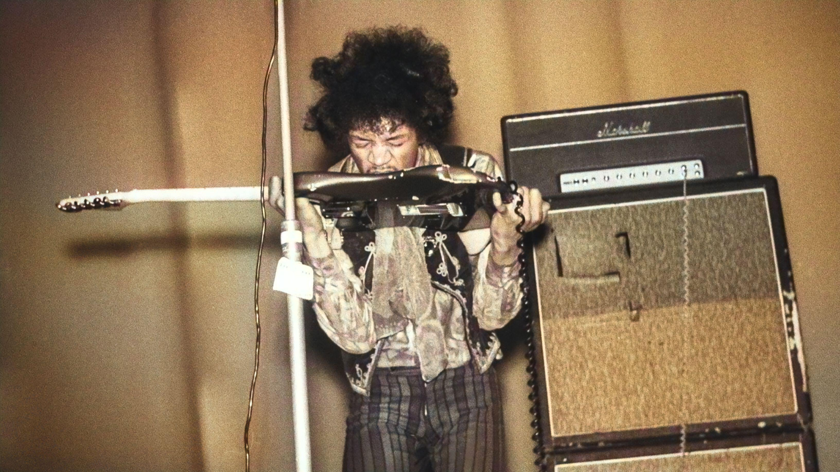 Jimi Hendrix playing guitar with his mouth