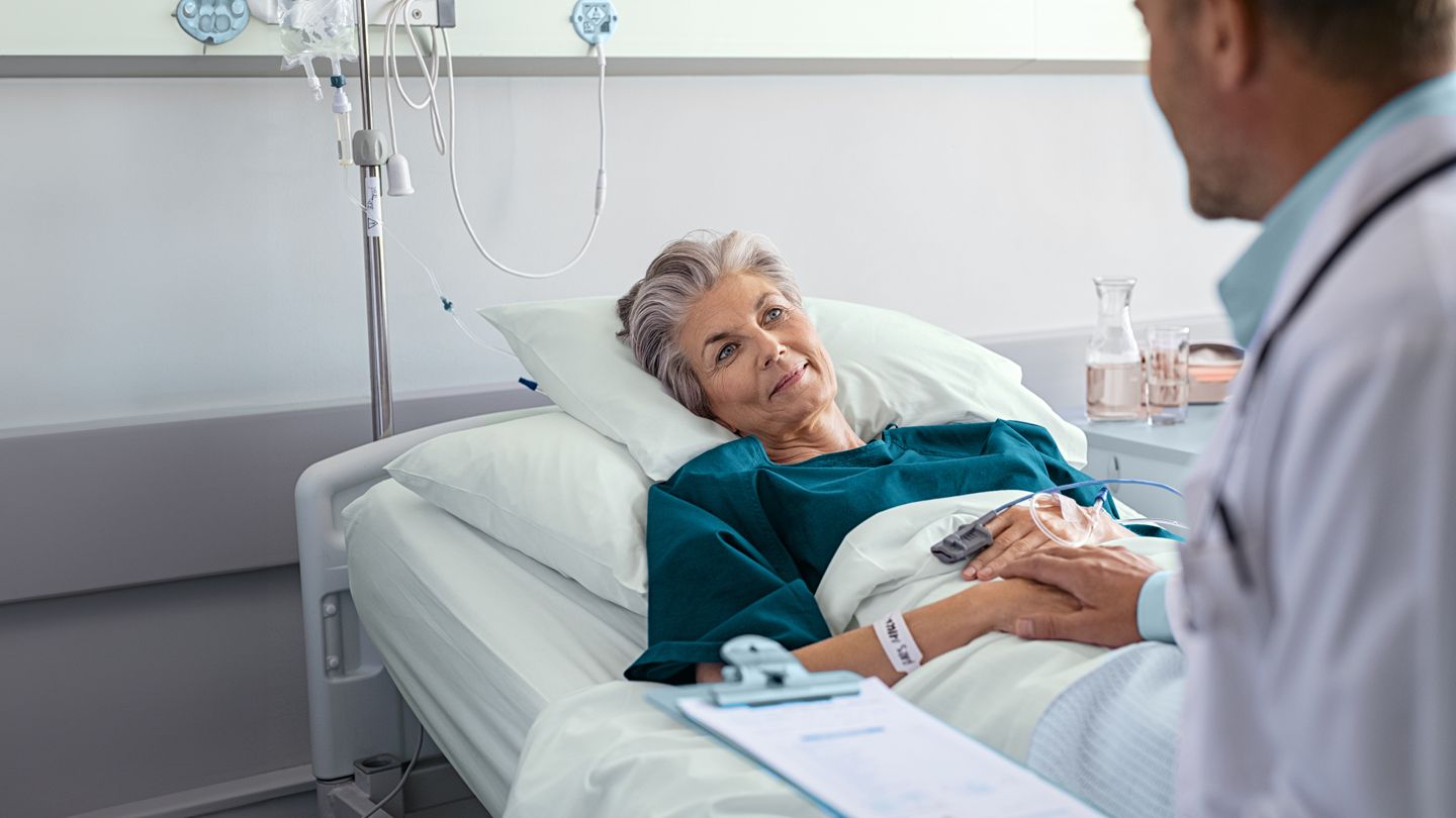 surgeon comforting patient after surgery in hospital recovery room