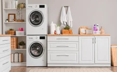 Tumble dryer and washing machine stacked next to white cabinets