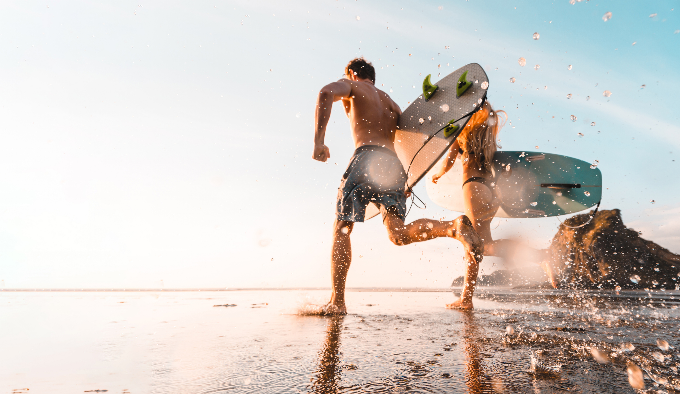 A couple surfing on Piha Beach, Auckland, New Zealand