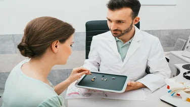 pharmacist shows lady different types of hearing aids