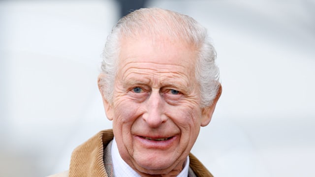 king charles smiling in cream collared coat