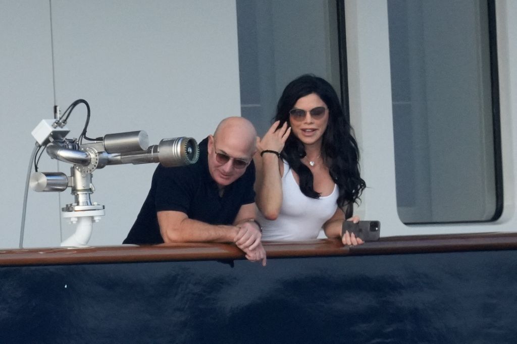 Lauren Sanchez runs her hand through her hair as she stands with Jeff Bezos