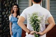 Man Holding Baby's-breath Flower in Front of Woman Standing Near Marble Wall