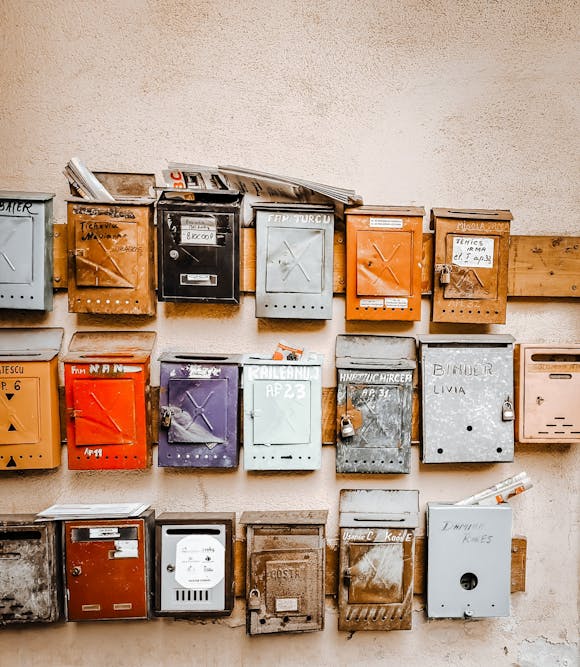 Many mailboxes of different colours stacked up next to one another