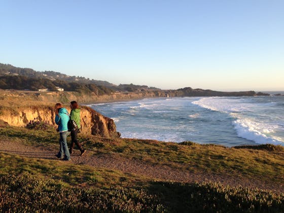 Two people walking along the bluff trail at Sea Ranch on the Sonoma Coast overlooking the Pacific Ocean