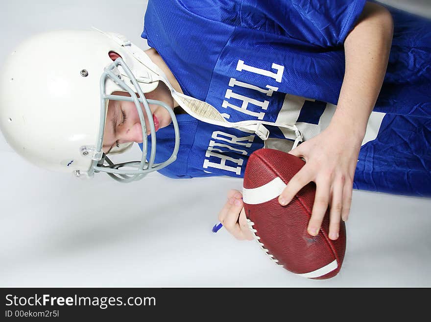 A young teen football MVP autographs a ball. A young teen football MVP autographs a ball