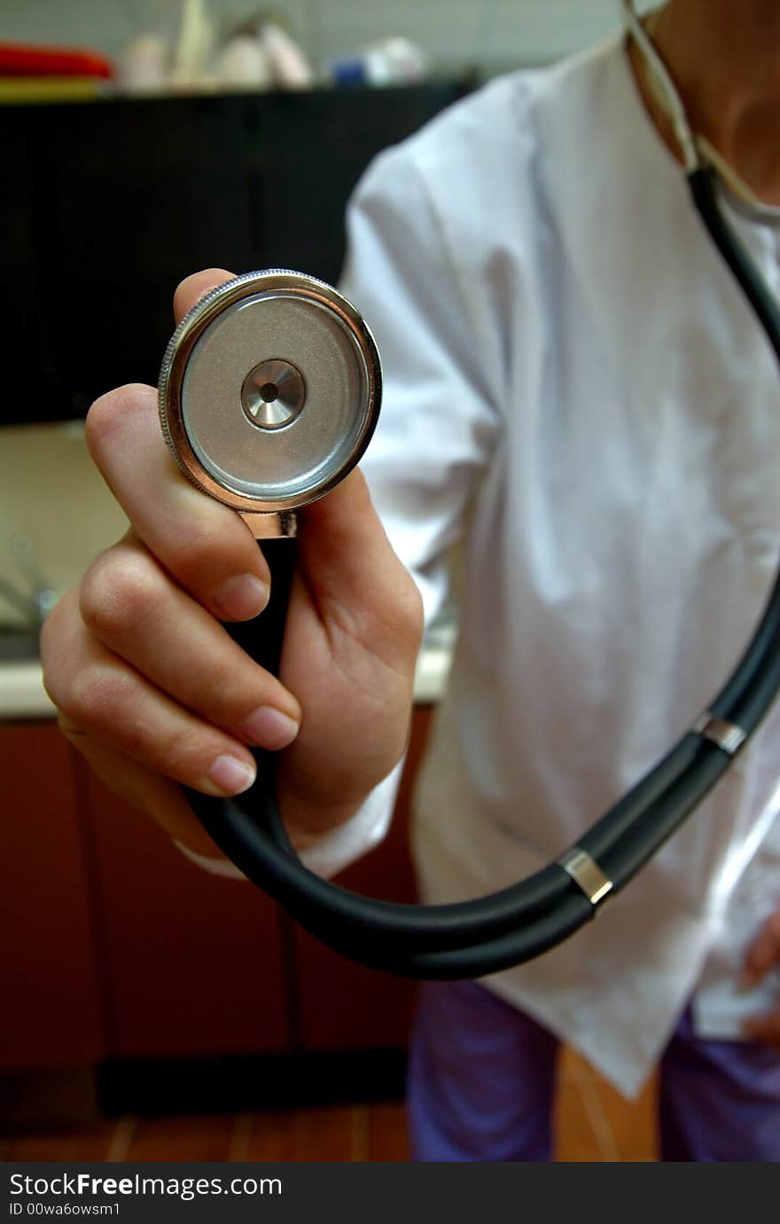 A stethoscope being held up to the camera lens being held by a female doctor in white lab coat. A stethoscope being held up to the camera lens being held by a female doctor in white lab coat.