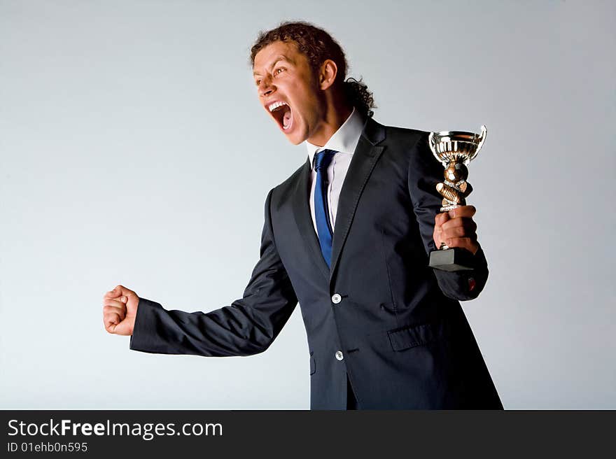 Half body portrait of successful sportsman holding trophy and shouting in celebration, white background.