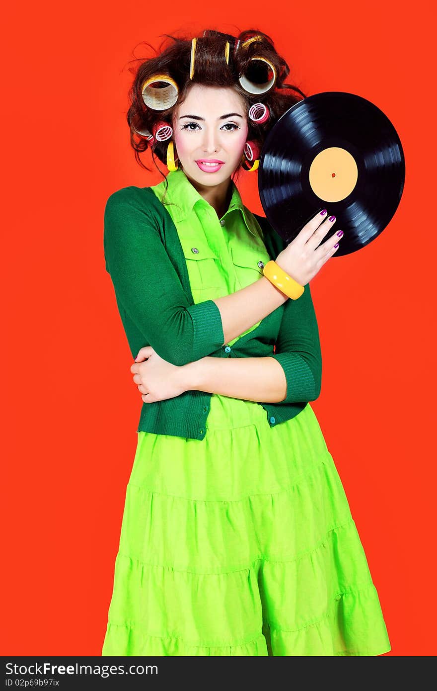 Portrait of a woman with curlers on her hair holding gramophone record. Retro style.