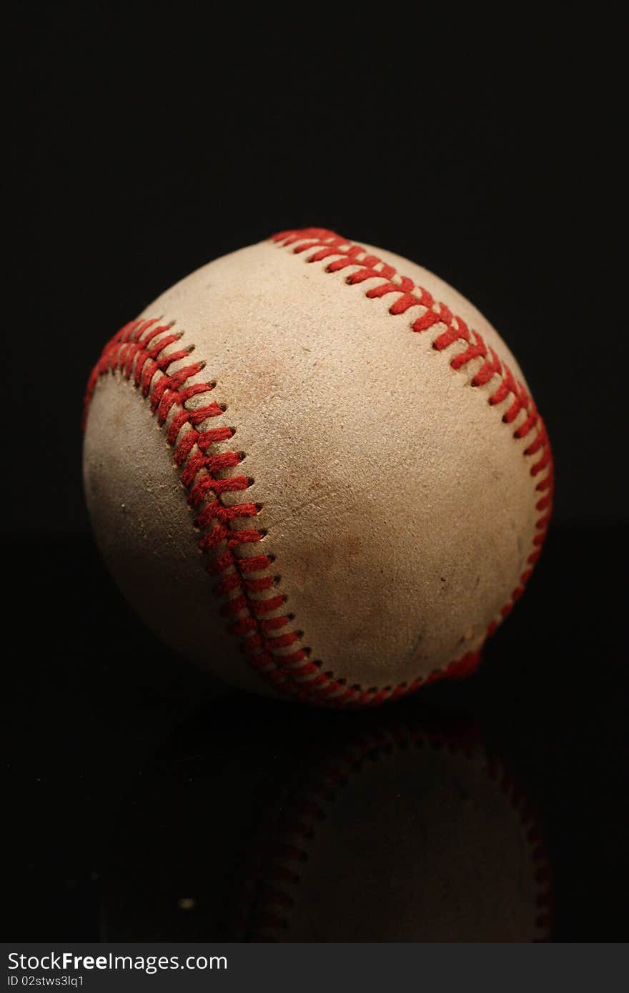 Closeup of a baseball against a black background.