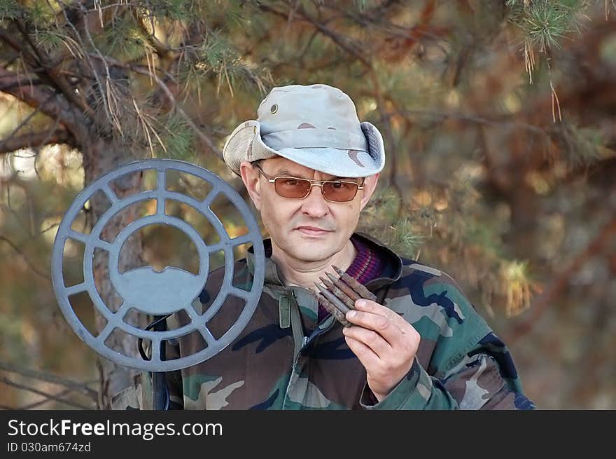 Military archeology. Man with metal detector and excavated German cartridges 7.92 mm caliber on the battlefield of WW2.Ukraine