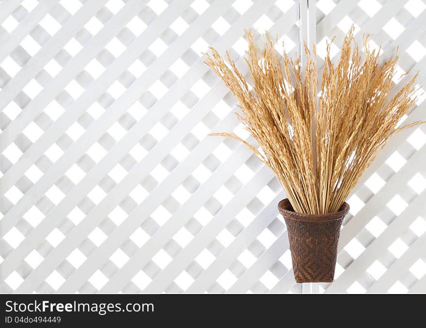 Wooden lattice background with golden rice spikes in bamboo basket