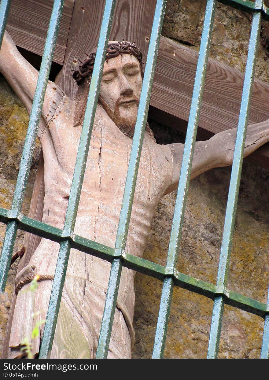 Statue of jesus christ on the cross behind bars