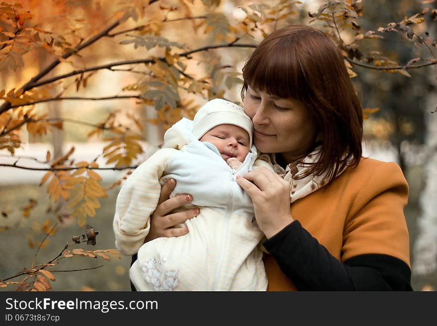 Newborn on the mother hands in autumn