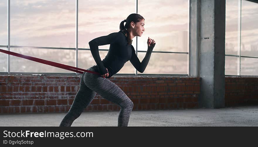 Woman athlete doing exercise with sports rubber in the gym