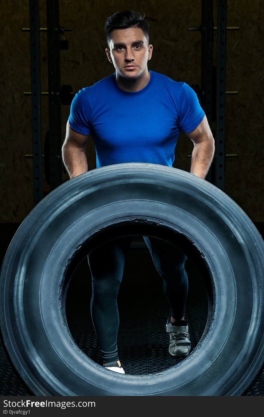 portrait of a strong athlete with a large heavy wheel